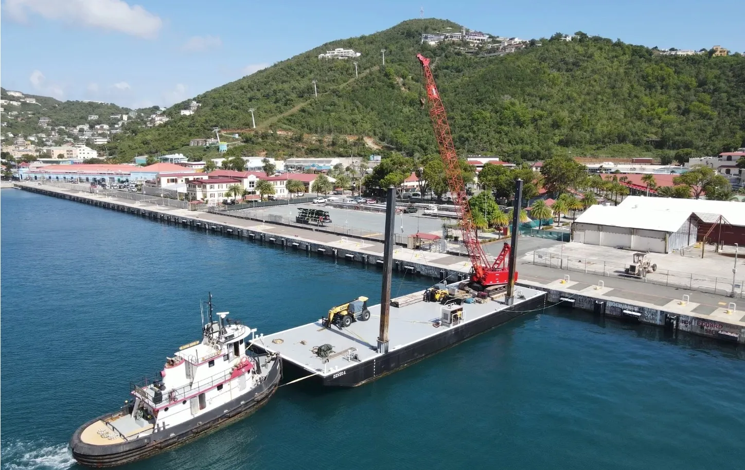 Barge delivery to the islands Tug alongside a deck barge carrying a crawler crane at a harbour quay