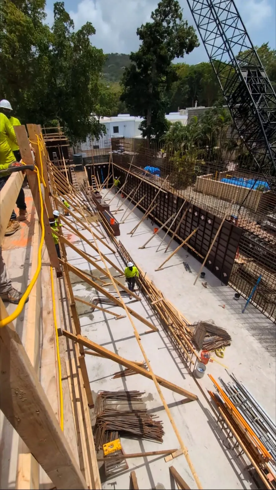 Formwork and rebar standing up for the plant's cistern walls, the crane rigged over the pour