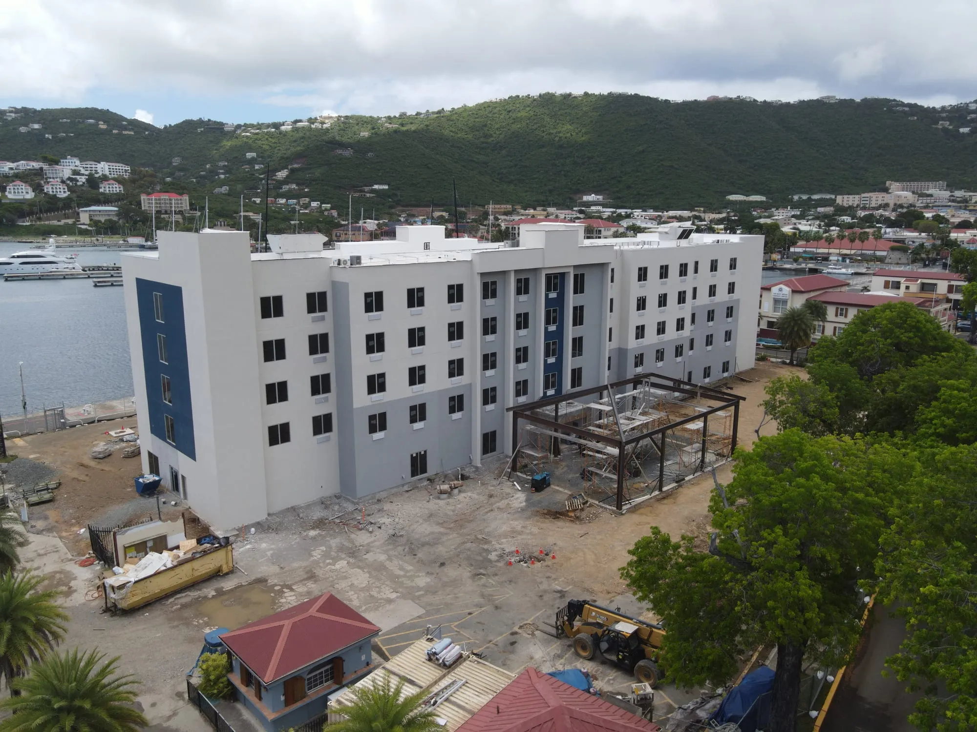 The finished hotel from the street, five stories of white concrete structure against the hillside