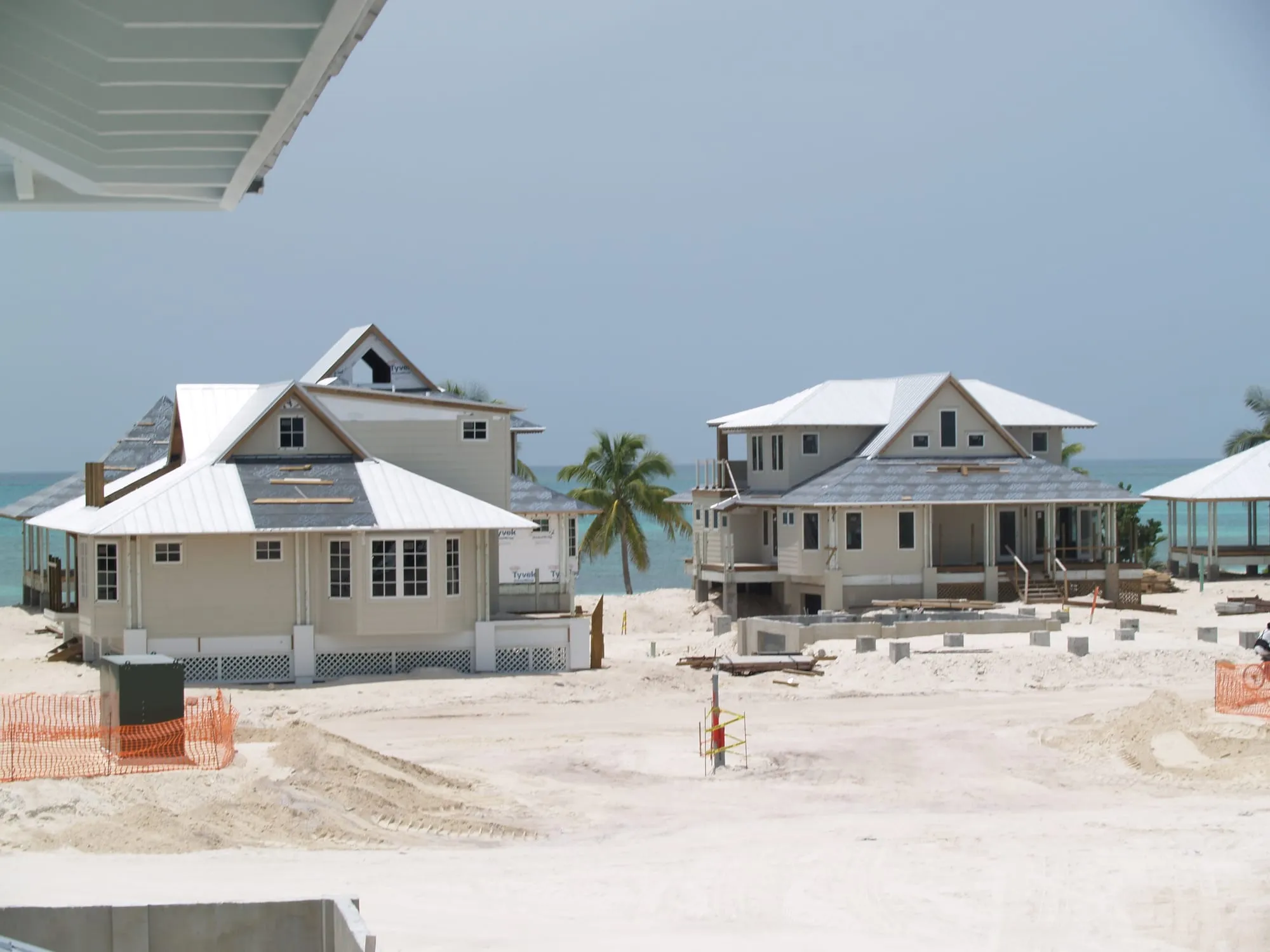 Two completed houses on the sand, roofs and porches finished