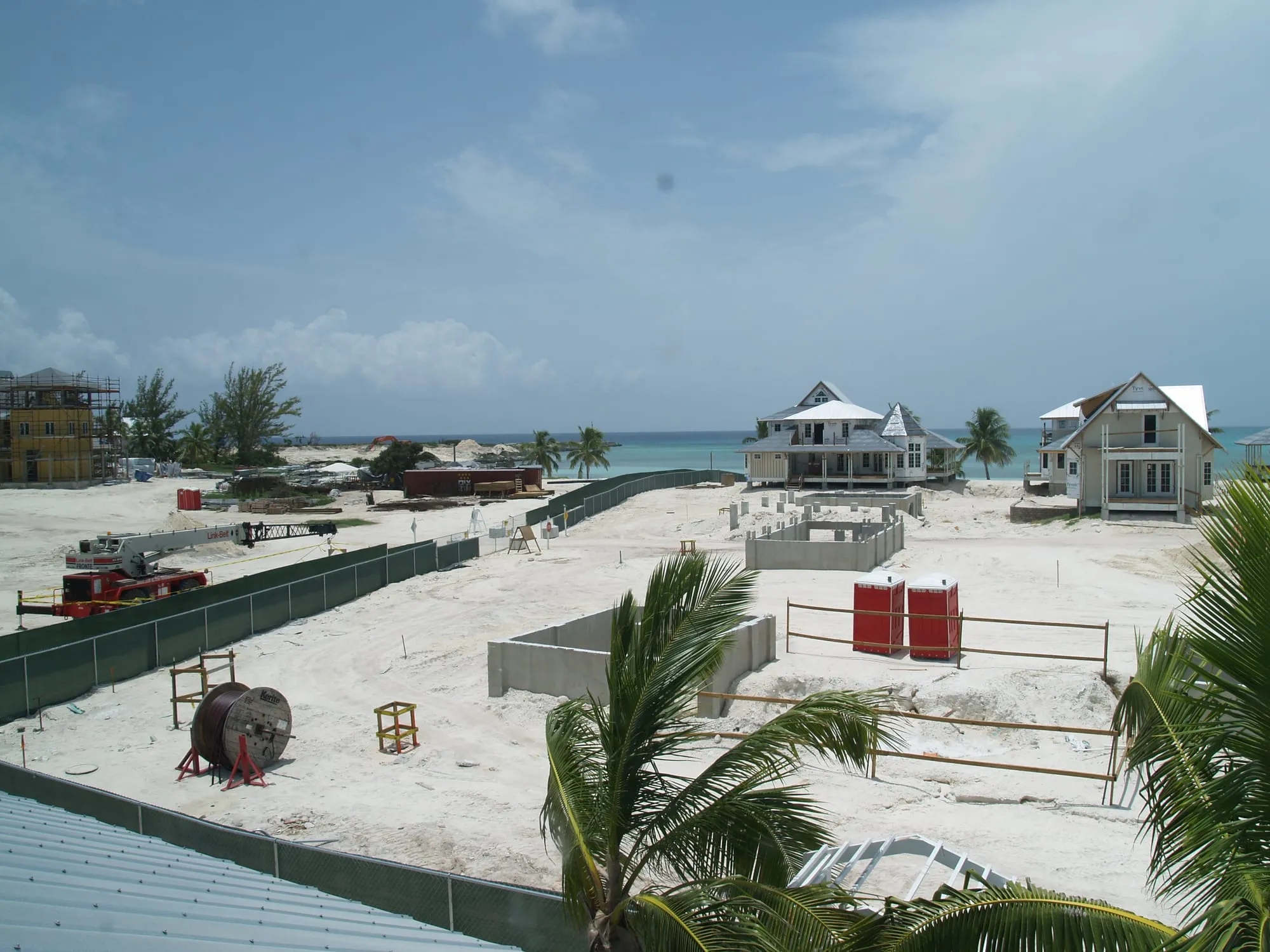Housing under construction behind the site fence, with the beach beyond