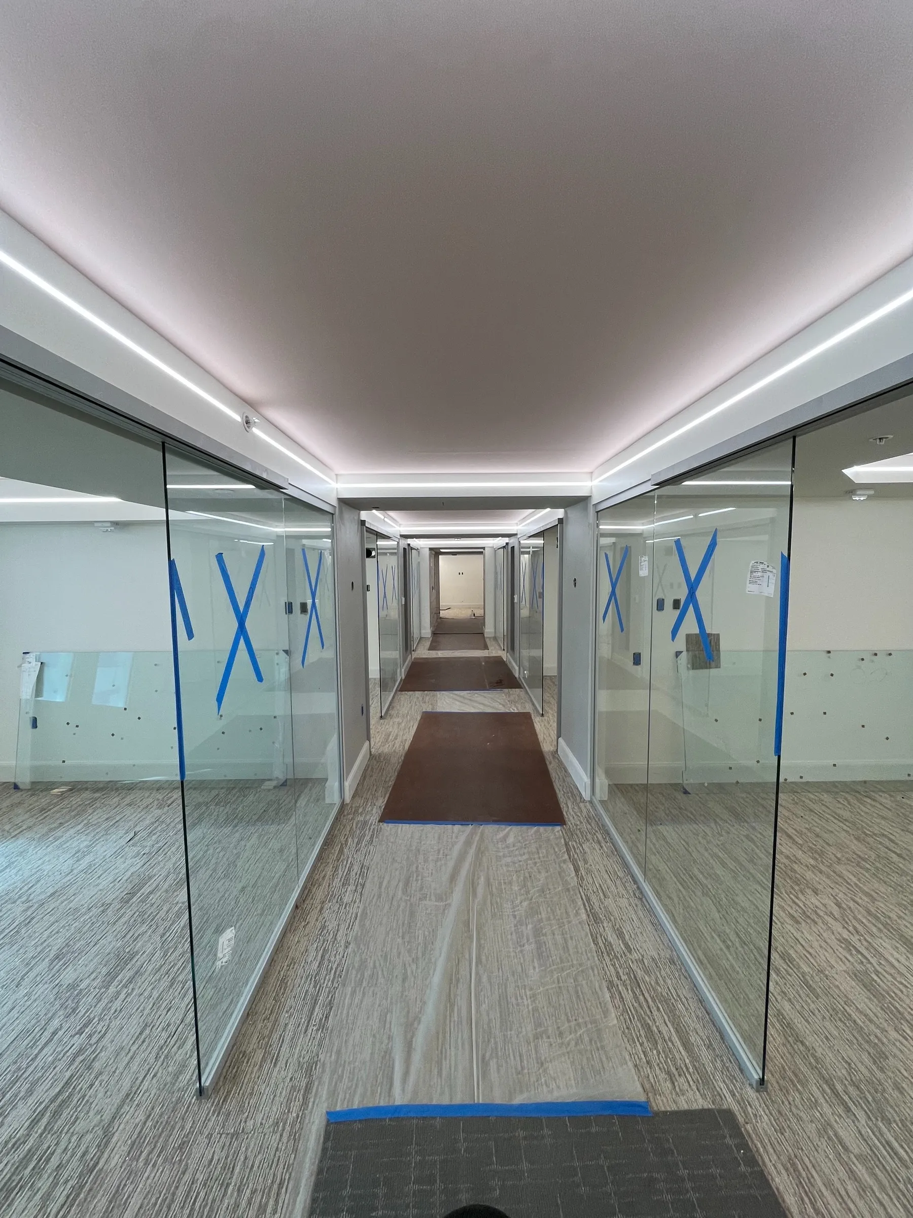 Glazed corridor protected with tape and floor covering during fit-out