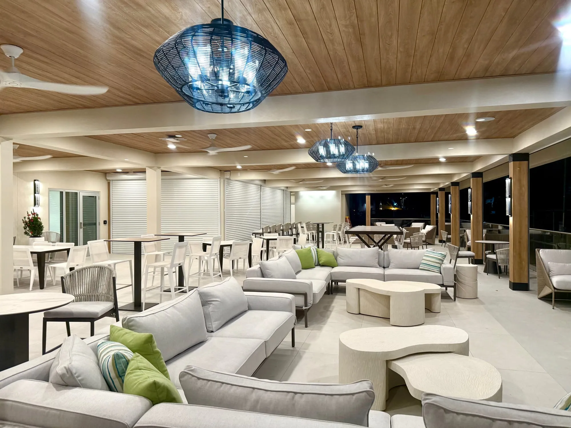 The hotel's covered outdoor lounge at dusk, under a timber ceiling and woven pendants