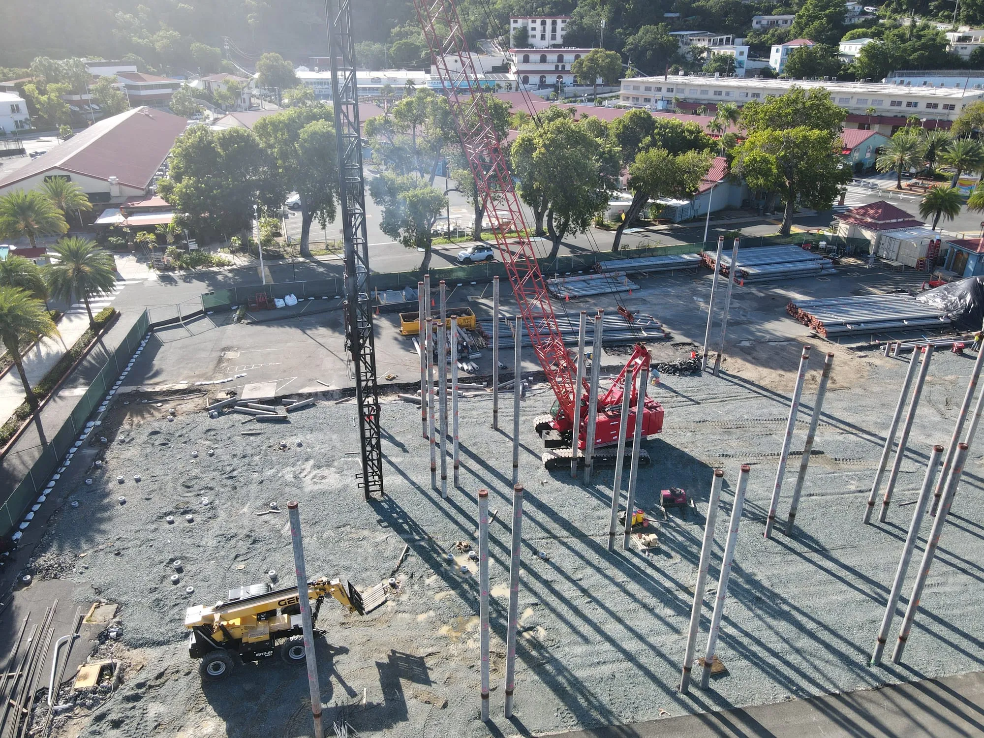 Aerial view of pile driving under way, with driven piles standing across the site