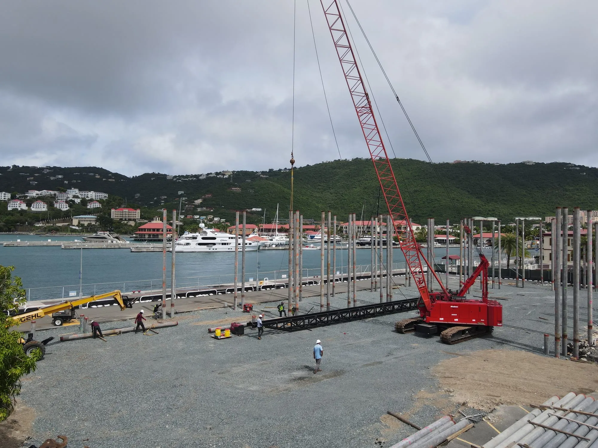 A red crawler crane driving spun piles on the waterfront site