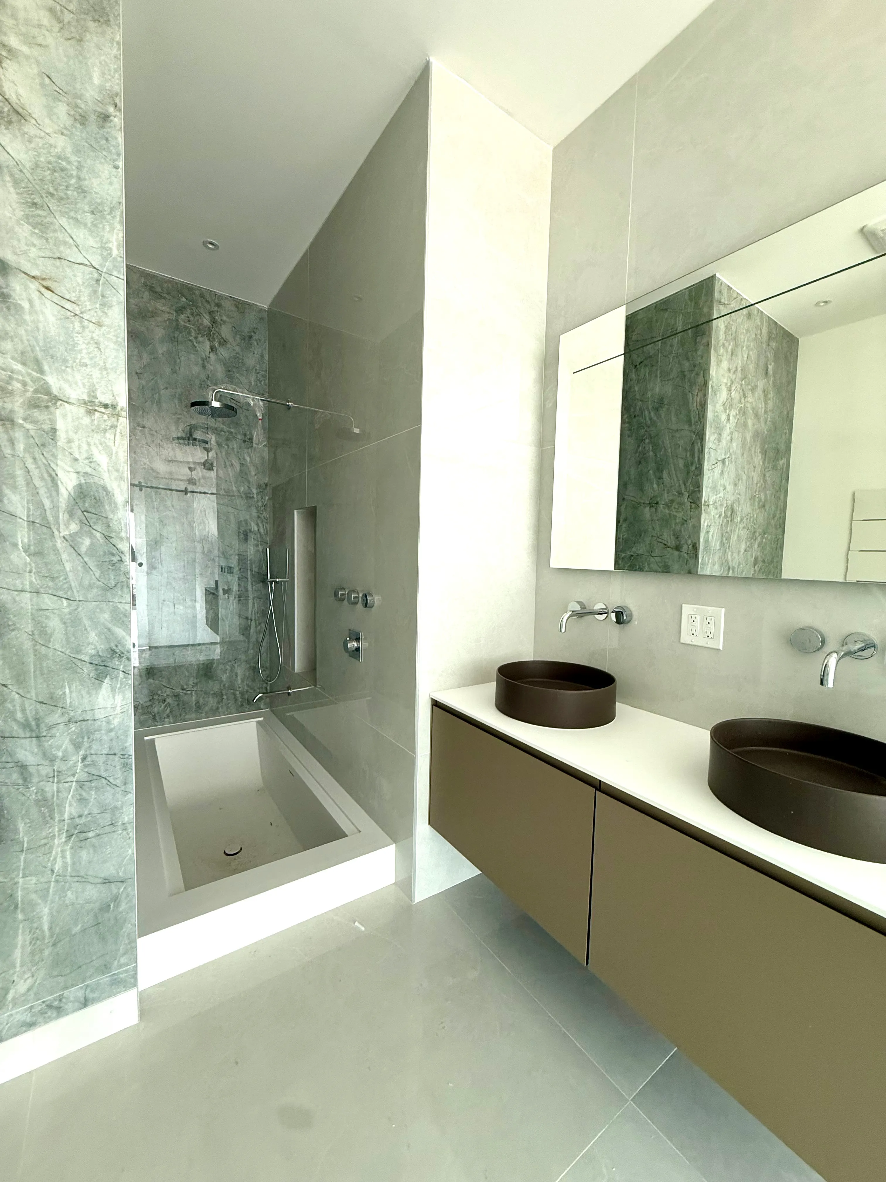 Design and construction carried through to the finishes A finished bathroom with a stone-clad shower, a sunken tub and a twin-basin vanity